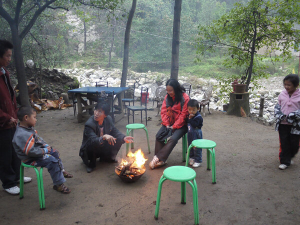 烤火
下雨，天气比较冷，农家主人点着了火盆，几个游人在院子里向火。
